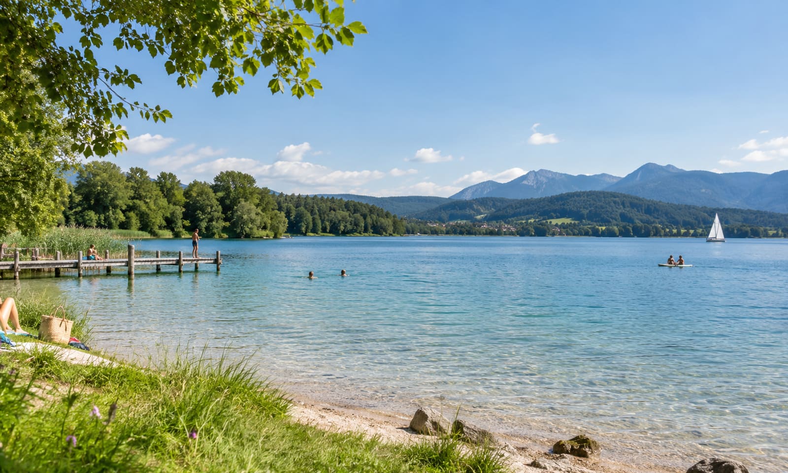 Badesee mit flach abfallendem Ufer, Liegewiese und Badegästen an einem Sommertag